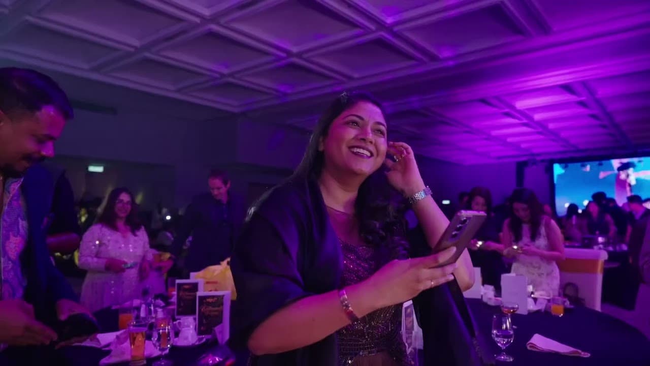 A guest laughs under purple stage lighting at a corporate event